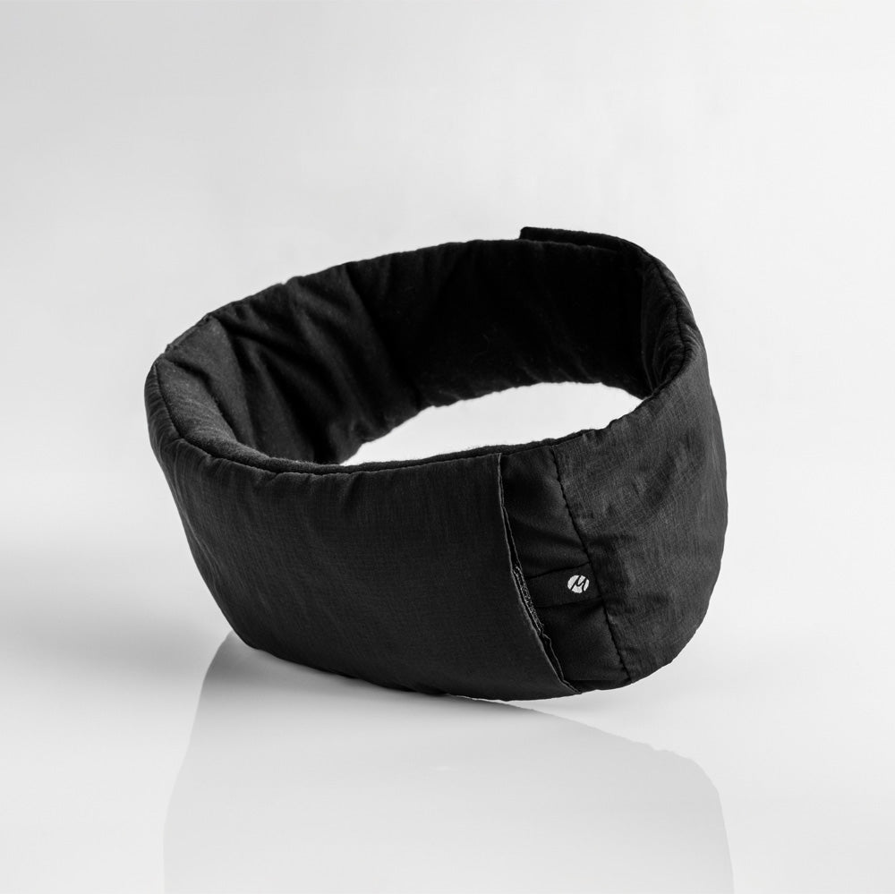 circular black eye mask sitting on reflective light gray background