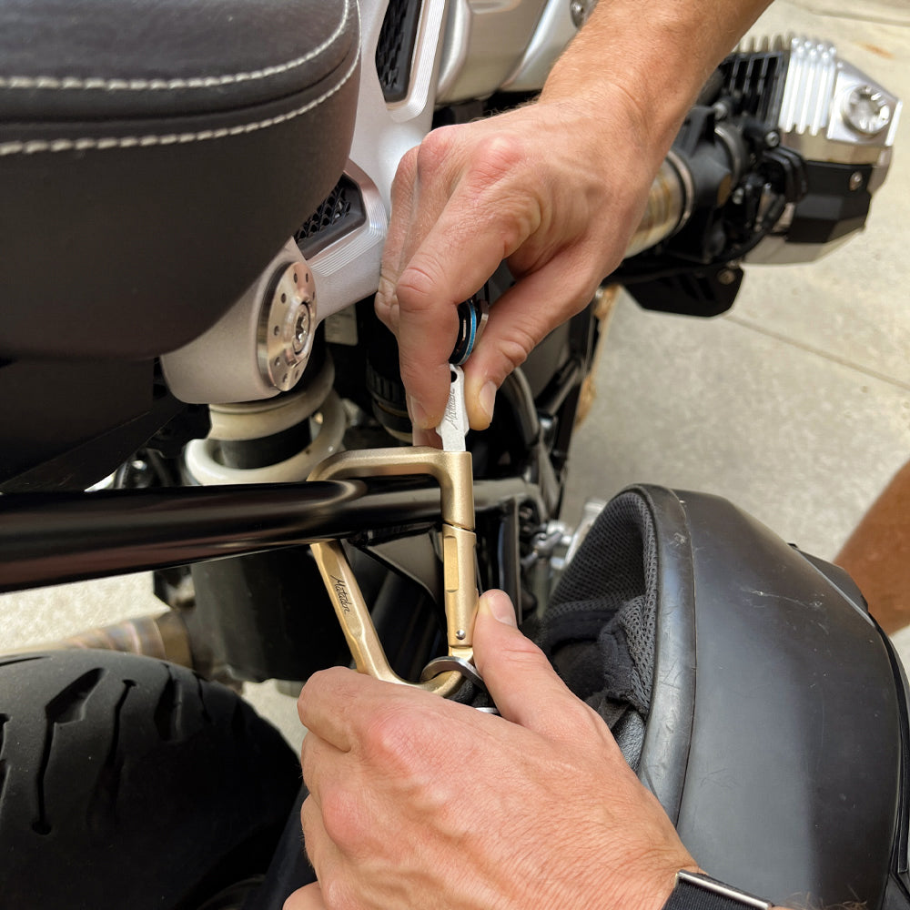 hands unlocking gold carabiner from motorcycle