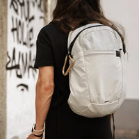 gold carabiner hanging off woman's white backpack