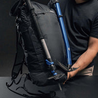 Man holding backpack with trekking pole and ice axe attached