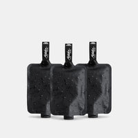 3 charcoal FlatPak Toiletry Bottles on light gray background