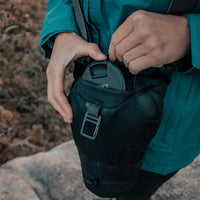Woman placing lens cap into front zipper compartment of baselayer