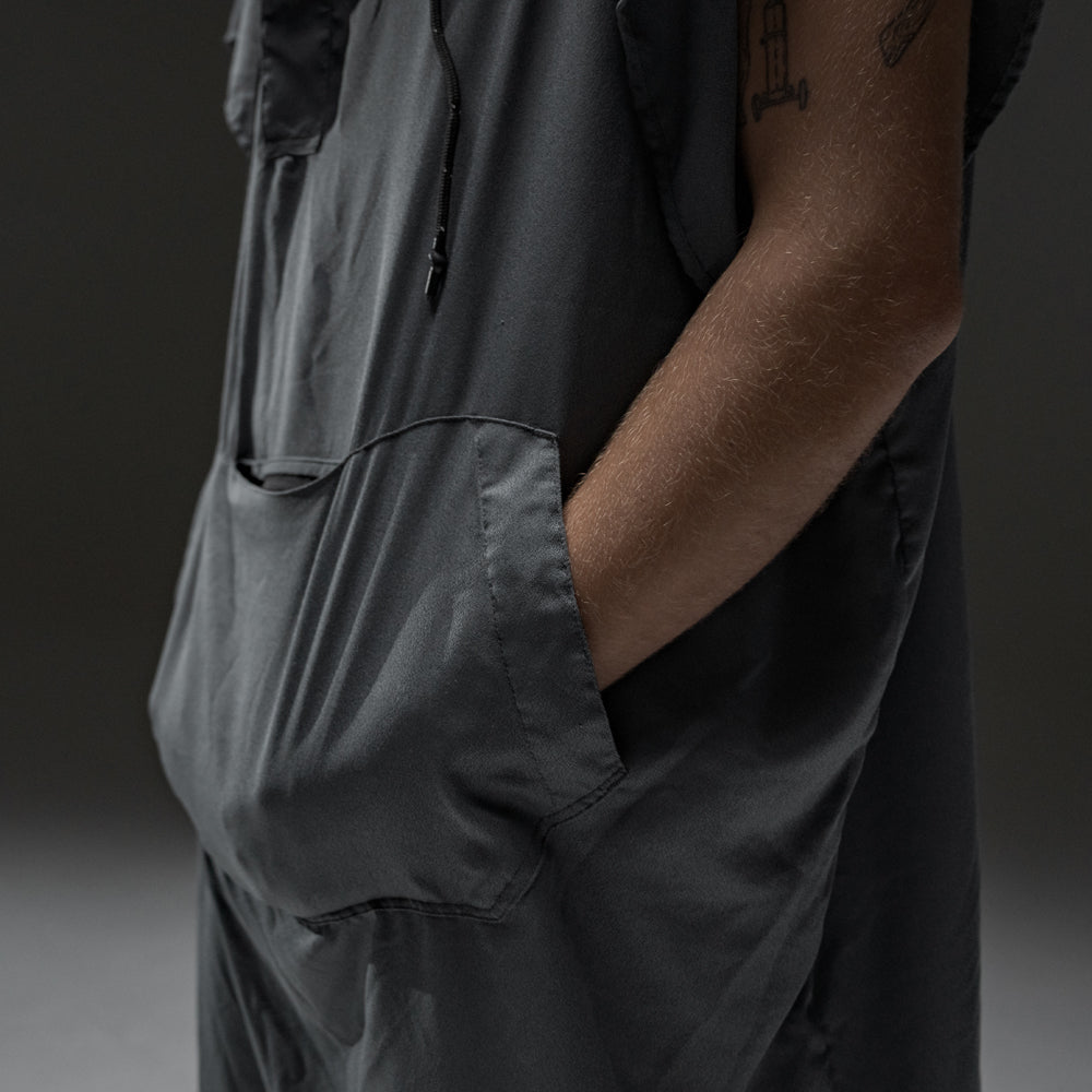 man in front of gray background with both hands in charcoal poncho kangaroo pocket