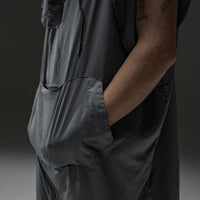 man in front of gray background with both hands in charcoal poncho kangaroo pocket