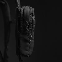 Close up side view of speed stash attached to black backpack strap