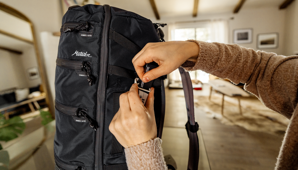 Woman attaching gear tag to black backpack