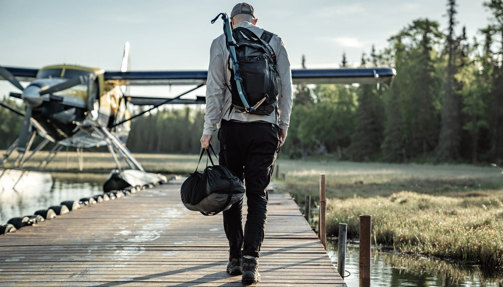 Man walking on dock, toward a sea plane, carrying the Freefly Duffle