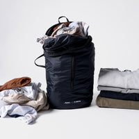 Full laundry bag on white background with dirty laundry to the left and folded laundry to the right