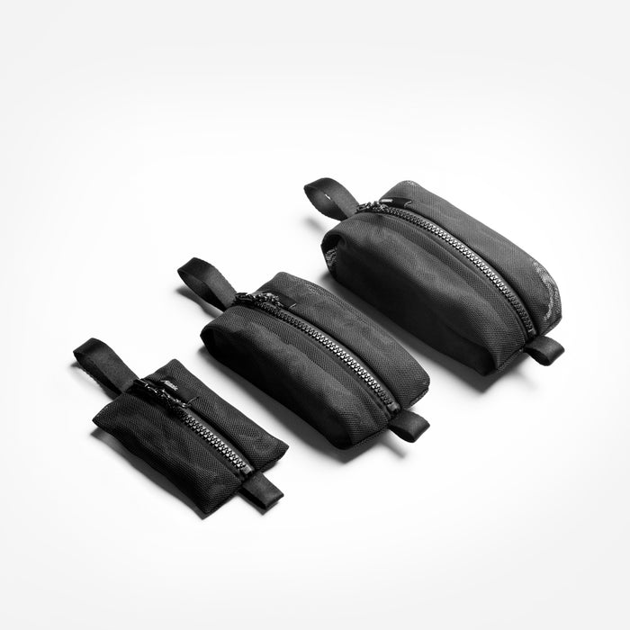 3 black mesh bags in varying sizes, stuffed, laying on light gray studio background
