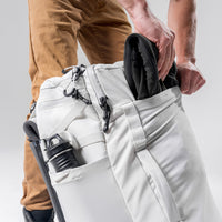 man stuffing black jacket into front stuff sack of white Globerider45